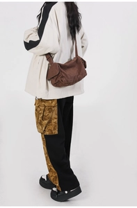 Rear view of a model wearing a retro dark brown canvas messenger bag in streetwear style