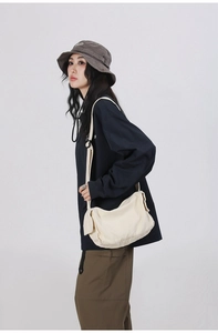 Detailed shot of white canvas crossbody bag with side flap pocket and adjustable strap