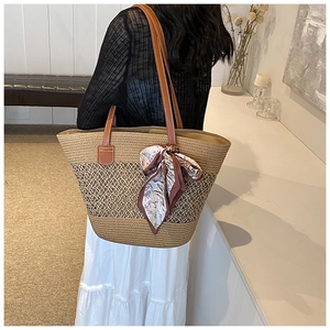 Détail d'un sac cabas en paille tressée avec lanières en cuir et foulard vintage décoratif
