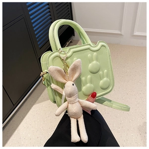 Detail of light green square bag with rabbit embossing and white knitted charm