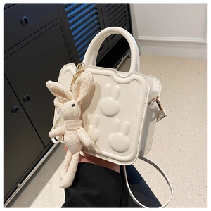 Detail of creamy white crossbody bag with 3D rabbit reliefs and a cute bunny pendant