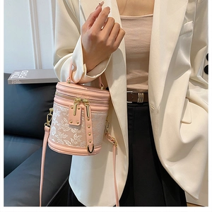 Detail of pink leather cylinder bucket bag with floral lace embroidery and gold studs
