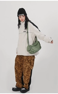 Army green canvas crossbody messenger bag with multiple pockets on urban streetwear outfit