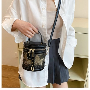 Detail of black bucket bag with gold butterfly embroidery and dual metal zippers