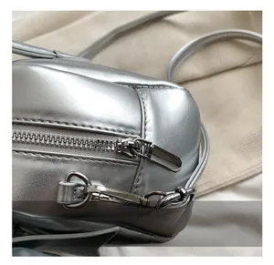Close-up of shiny silver metallic zipper and high-quality hardware on a texture leather bag