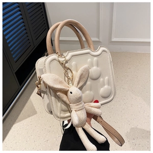 Detail of off-white handbag featuring 3D rabbit embossing and a knitted bunny charm
