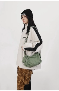 Detail view of a green washed canvas crossbody bag with adjustable wide strap on a model