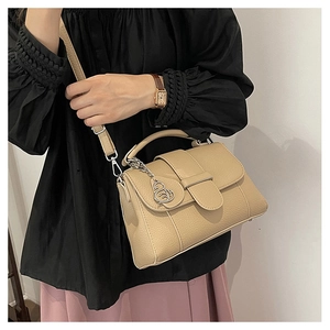 Detail of beige lychee pattern leather handbag with elegant silver swan pendant