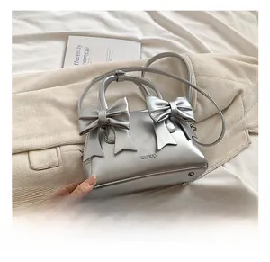 Detail of silver metallic pillow bag with bow accents and metal protective bottom studs