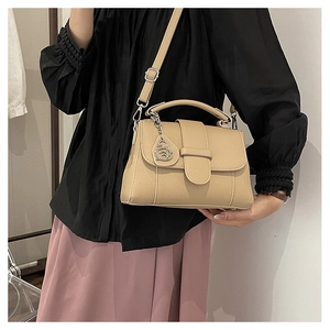 Close-up of beige lychee texture leather handbag with silver swan charm detail