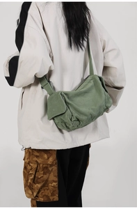 Detail view of a green canvas messenger bag with adjustable strap and side pocket design