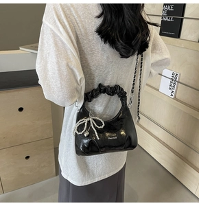 Détail du sac plissé noir avec nœud en perles et bandoulière chaîne pour femme