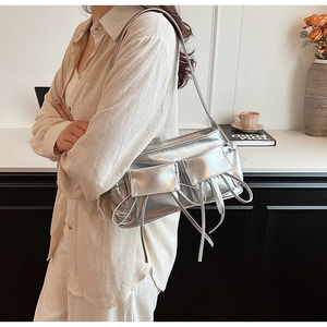 Detail of silver metallic underarm bag with double front pockets and glossy texture