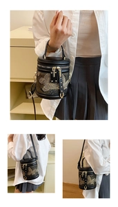 Detail of butterfly embroidery on a black bucket bag with gold zippers and metal hardware