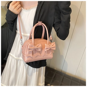 Detail of pink glossy patent leather handbag with bow accents and silver hardware