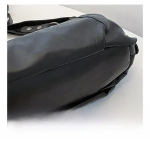 Macro detail of black pebble leather tote bag showing strap attachment and metal buckle