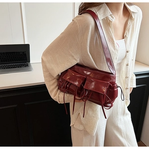 Detail of burgundy glossy PU leather shoulder bag with multi-pocket and drawstring design