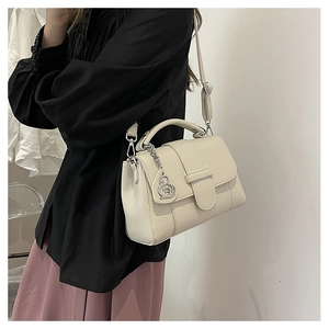 Detail of off-white lychee texture crossbody bag with silver metal charm and strap