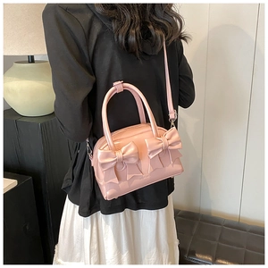 Pink bow-knot handbag displayed in a stylish home setting with a thin shoulder strap