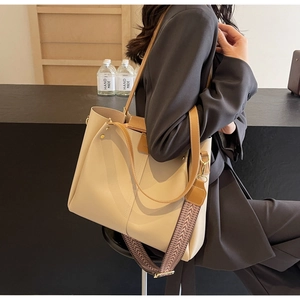 Détail d'un sac cabas beige avec anses en cuir marron et large bandoulière géométrique