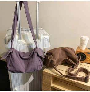 Detail of vintage canvas crossbody bags in purple and brown with side flap pockets