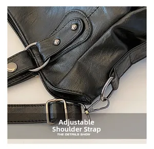 Detail of adjustable black leather shoulder strap with silver metal buckle and rivets