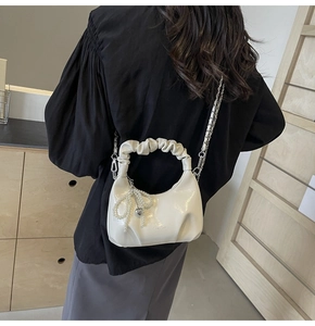 Détail du sac crème avec anse plissée, nœud en perles et breloque cœur sur chaîne