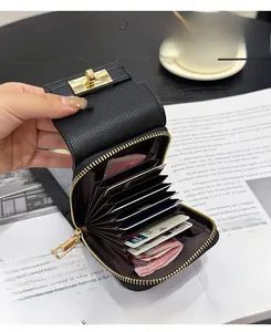 Detail of black lychee leather card holder featuring accordion slots and gold metal clasp