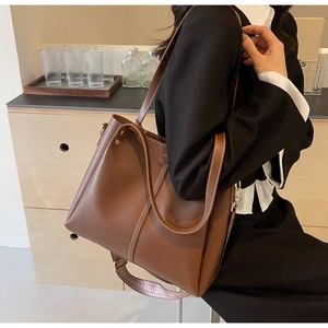 Dettaglio della grande borsa tote marrone con cuciture a contrasto e tracolla in tessuto
