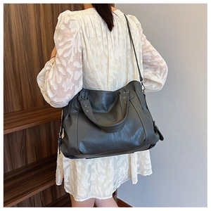 Grey large capacity tote bag shown on shoulder with stylish leather texture and studs