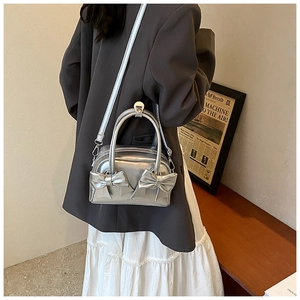 Detail view of silver bow-knot handbag with metallic finish and adjustable strap