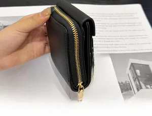 Detail of smooth gold metal zipper on black lychee grain leather mini wallet