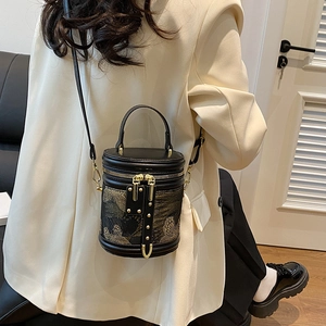 Elegant black embroidered bucket bag with gold hardware shown on a model in lifestyle setting