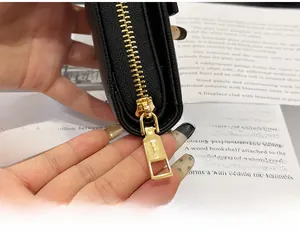 Close-up of premium golden metal zipper on black litchi grain leather mini wallet