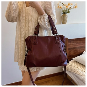 Detail of burgundy leather tote bag showing vintage metal rivets and strap texture