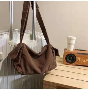 Detail view of brown canvas messenger bag hanging on suitcase with travel accessories