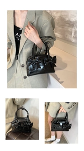 Detail view of black patent leather handbag with bow accents and top handle design