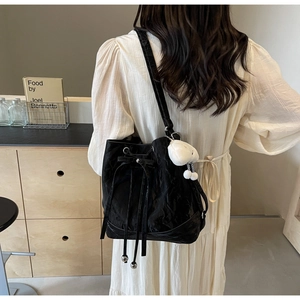 Detail der schwarzen Bucket Bag mit Kordelzug-Schleife und weißem Plüsch-Anhänger