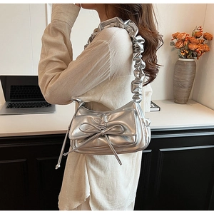 Detail of silver pleated crossbody bag featuring a large bow and soft ruffled strap