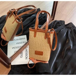 Détail d'un sac seau en paille avec bordure en cuir marron et bandoulière réglable