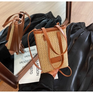 Détail du sac seau en paille tissée avec poignées en cuir marron et étiquette