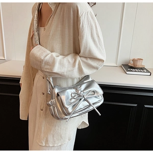 Close-up of metallic silver bow shoulder bag with pleated details and shiny PU finish