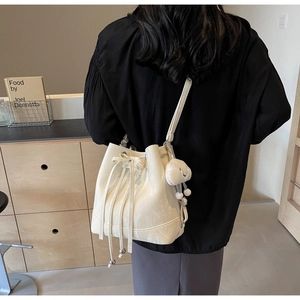 Detail der cremeweißen Beuteltasche mit Schleifenzug und süßem Wolkenanhänger