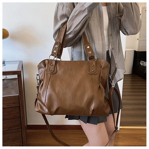 Brown tote bag detail showing matte wrinkled texture, metal rivets, and adjustable strap