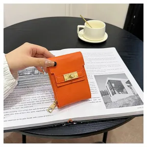 Detail of orange pebble leather mini bag featuring a gold turn-lock and side zipper