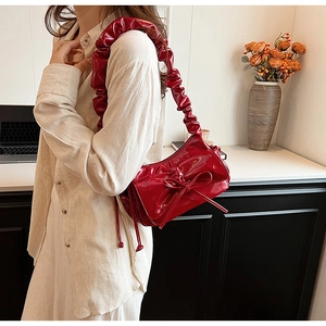 Red patent leather baguette bag with a bow detail and gathered ruched shoulder strap