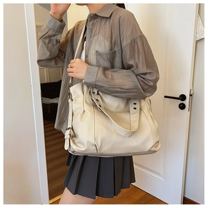 Detail of off-white large tote bag with pleated texture and adjustable strap on shoulder