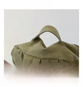 Détail du sac à dos en toile vert olive montrant la poignée et les bretelles rembourrées