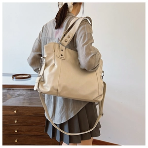 Detailed view of beige soft leather tote bag showing wide straps and side metal clips