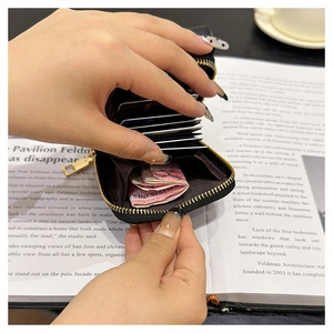 Detail of black pebble leather card holder with accordion slots and metal zipper